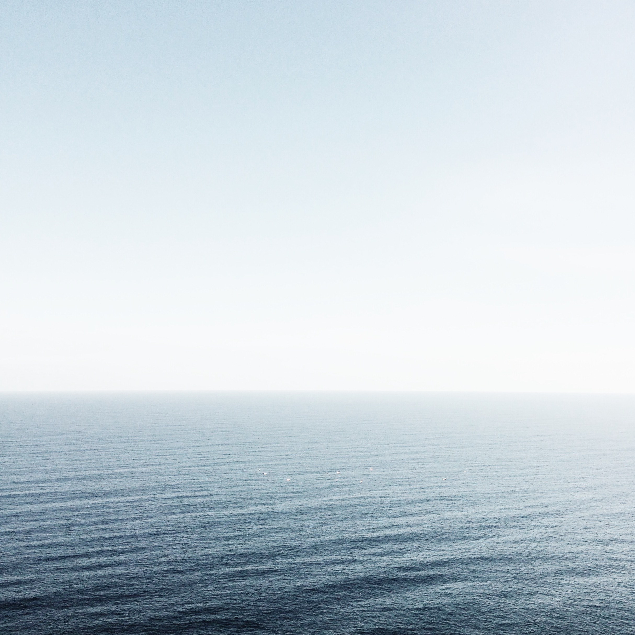 Vast expanse of calm blue ocean under pale sky, Scenic 4k Wallpaper