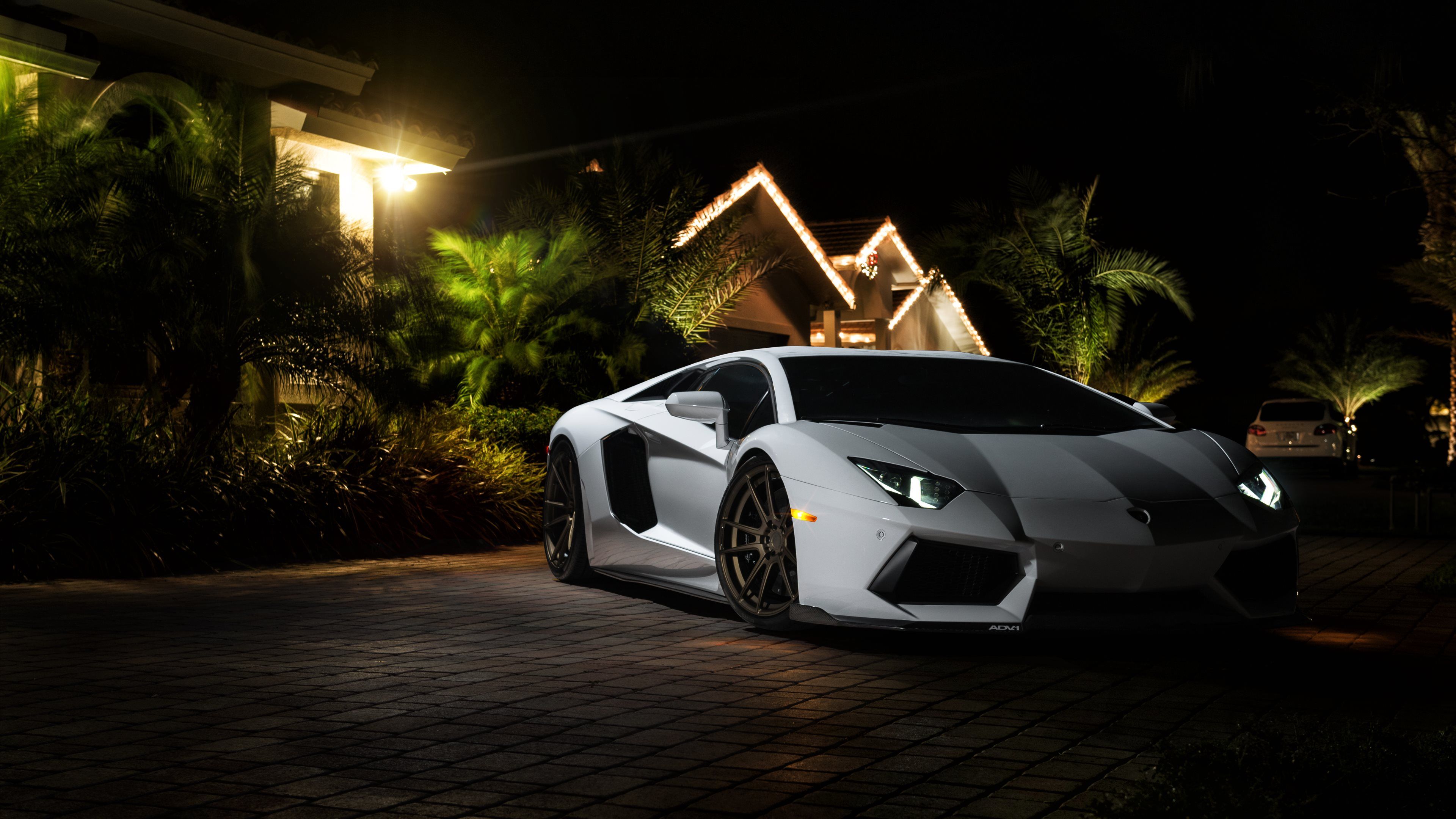 White Lamborghini Aventador parked in front of a house at night