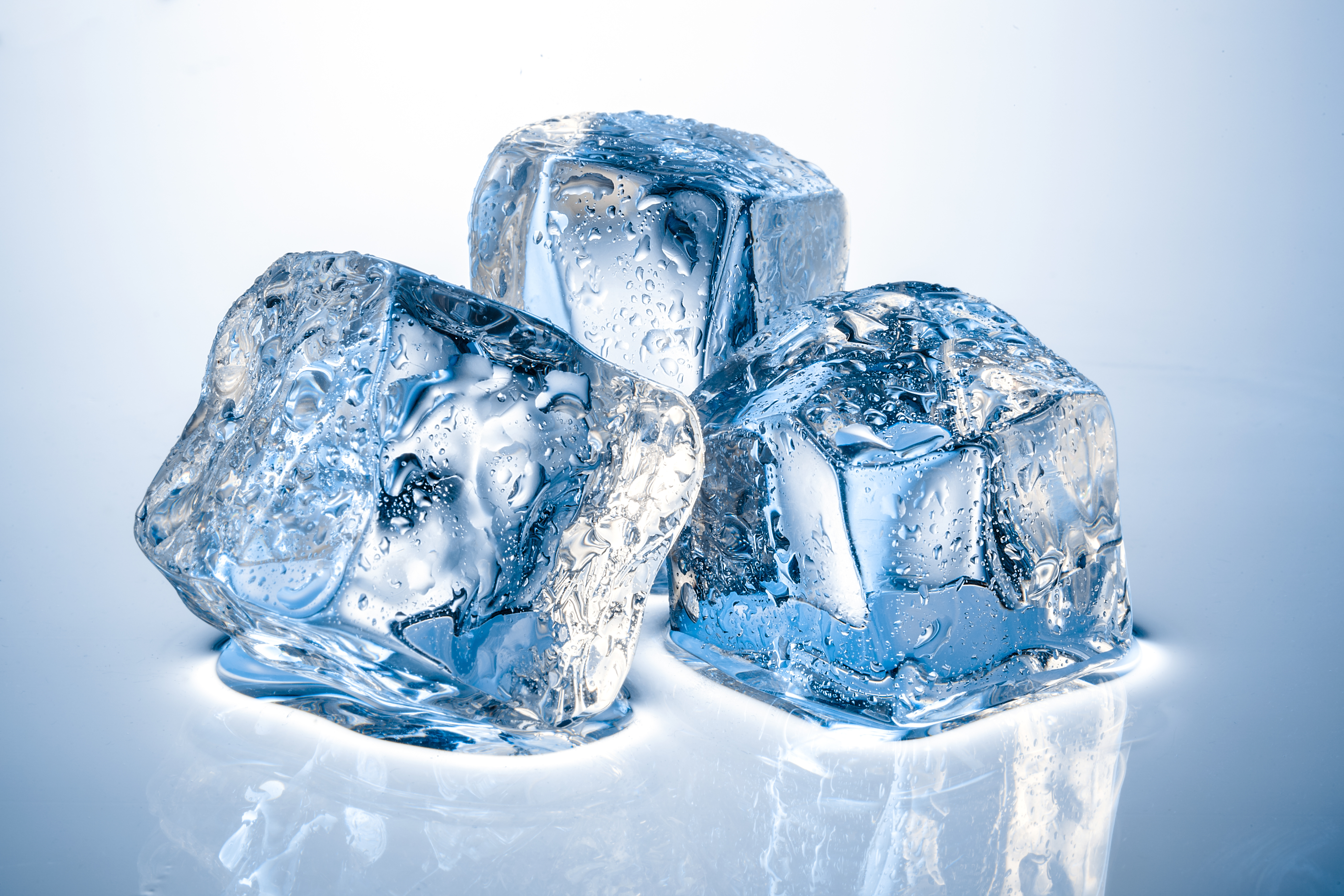 Three glistening ice cubes on a reflective surface