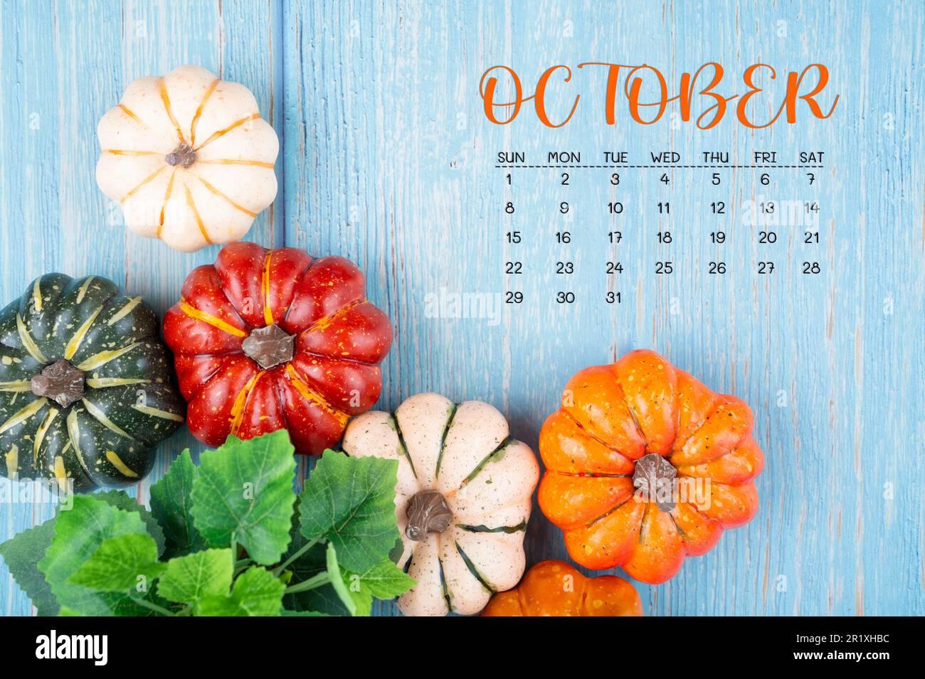 October 2023 Calendar and pumpkins on wooden color background