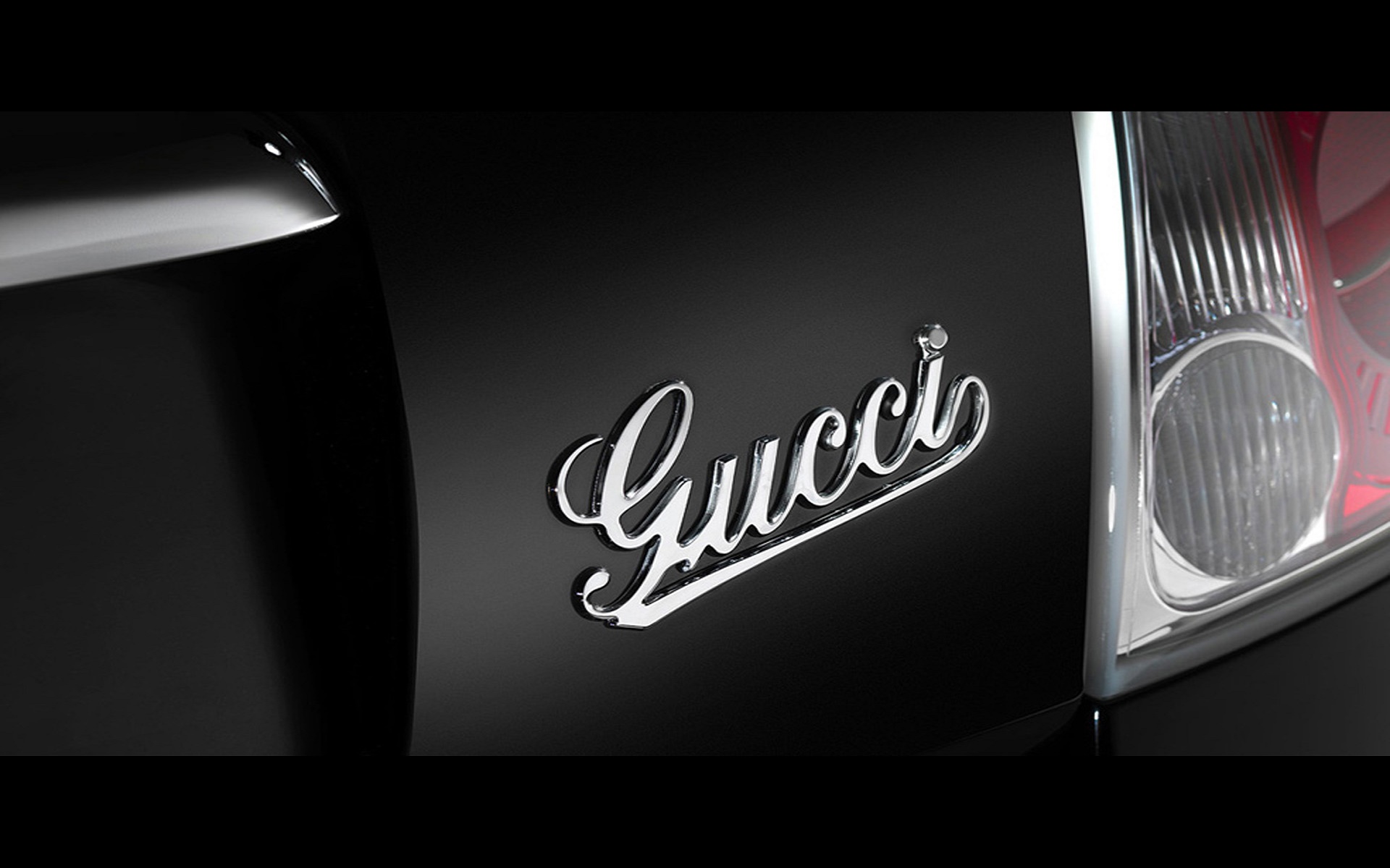 Close-up of a Gucci logo on a black car, showcasing the luxury collaboration between Gucci and the automotive industry