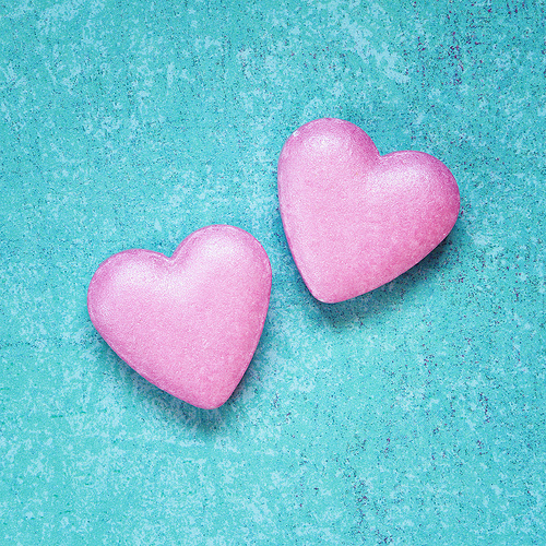 Two Pink Candy Hearts On Turquoise Textured Background