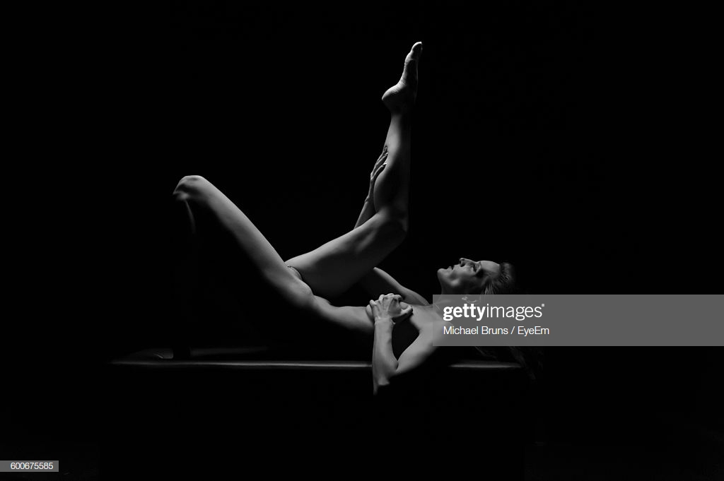Seductive Naked Athlete Woman Lying On Table Against Black