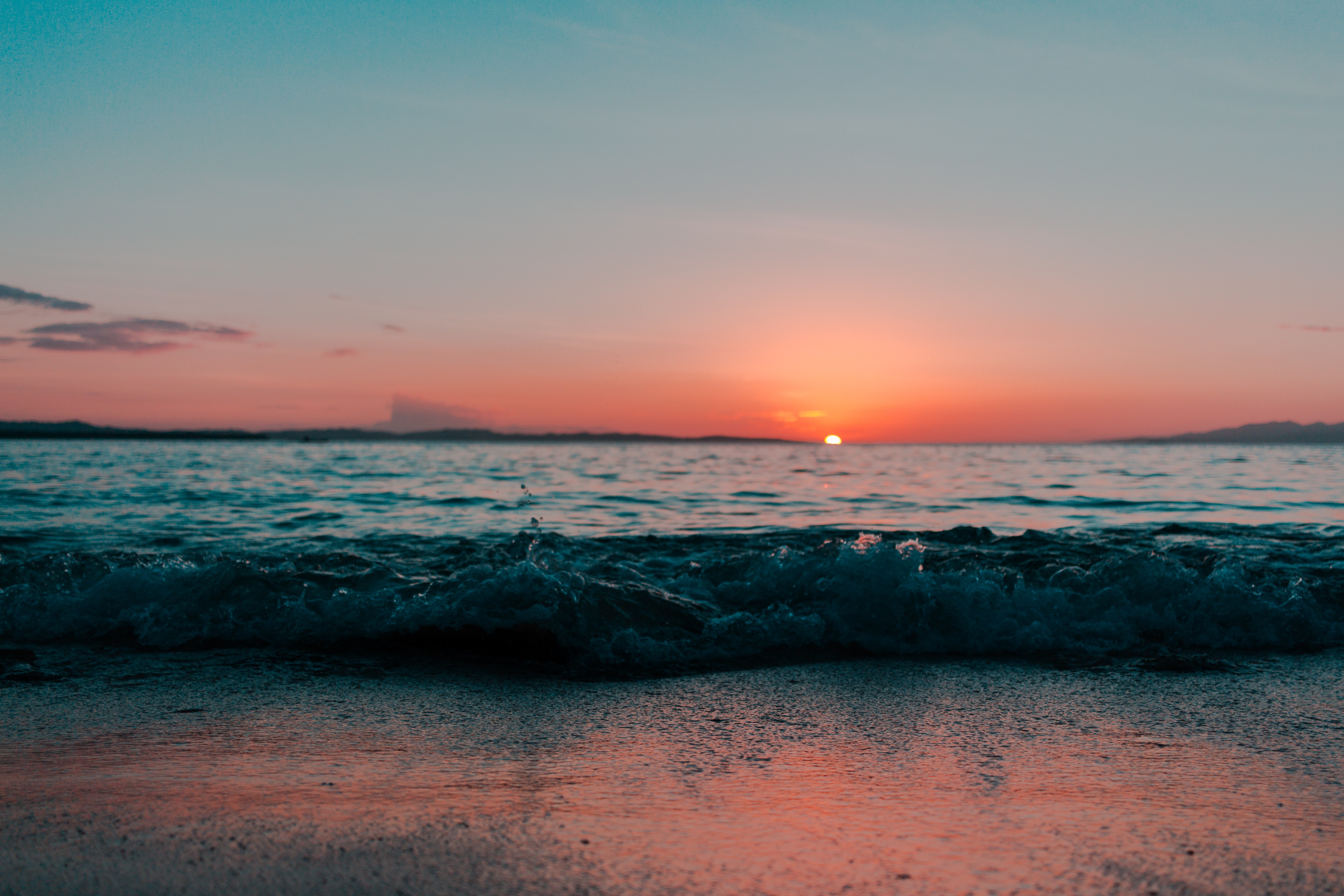 Sunset over a tranquil ocean with gentle waves lapping at the shore