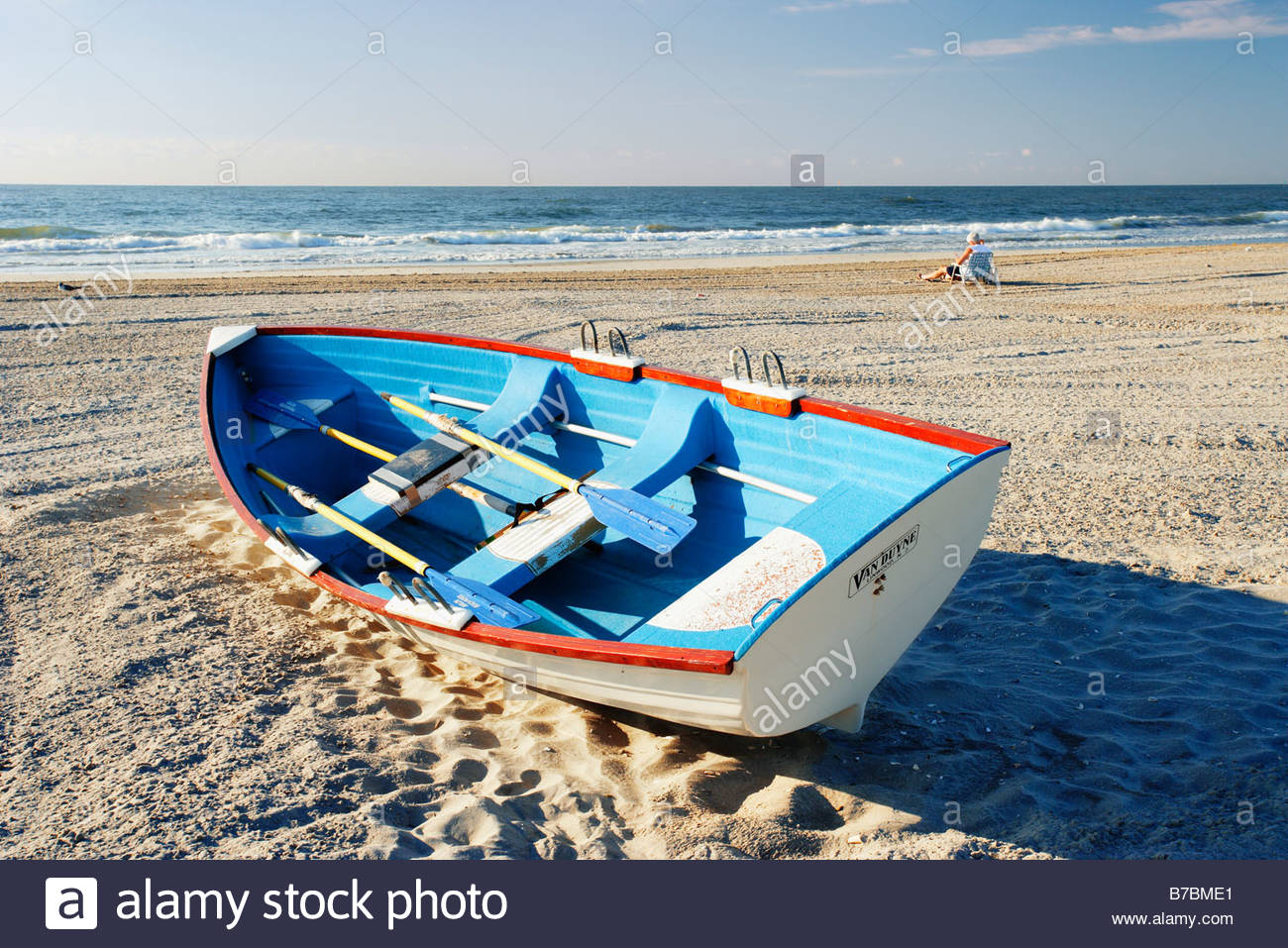 Mature Man In Background Sitting On Beach And Small Boat New