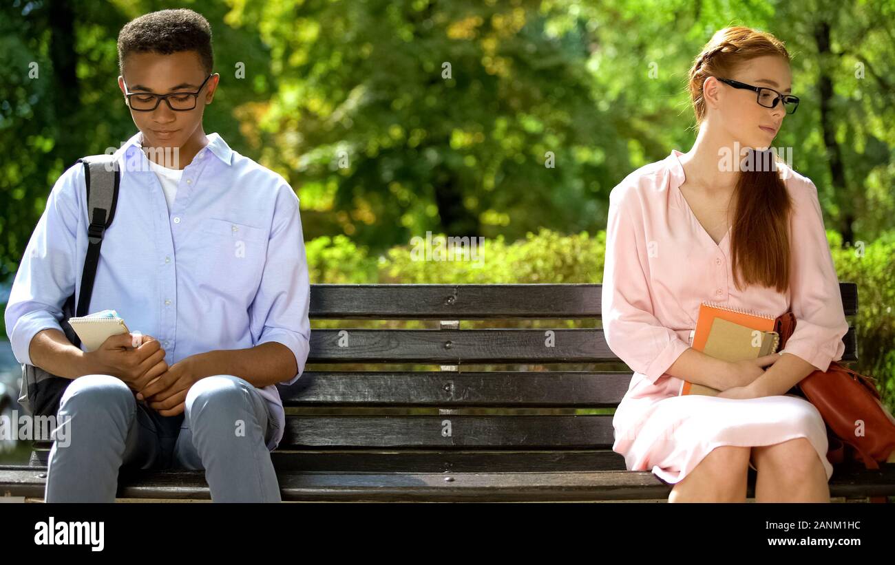 Shy Teens Sitting On Different Parts Of Bench Hesitating To Tell
