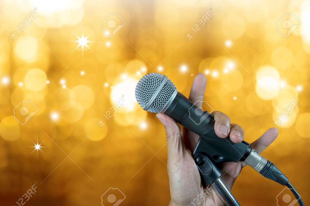 Hand Holding Microphone On Stand With Bokeh Glow Blurred