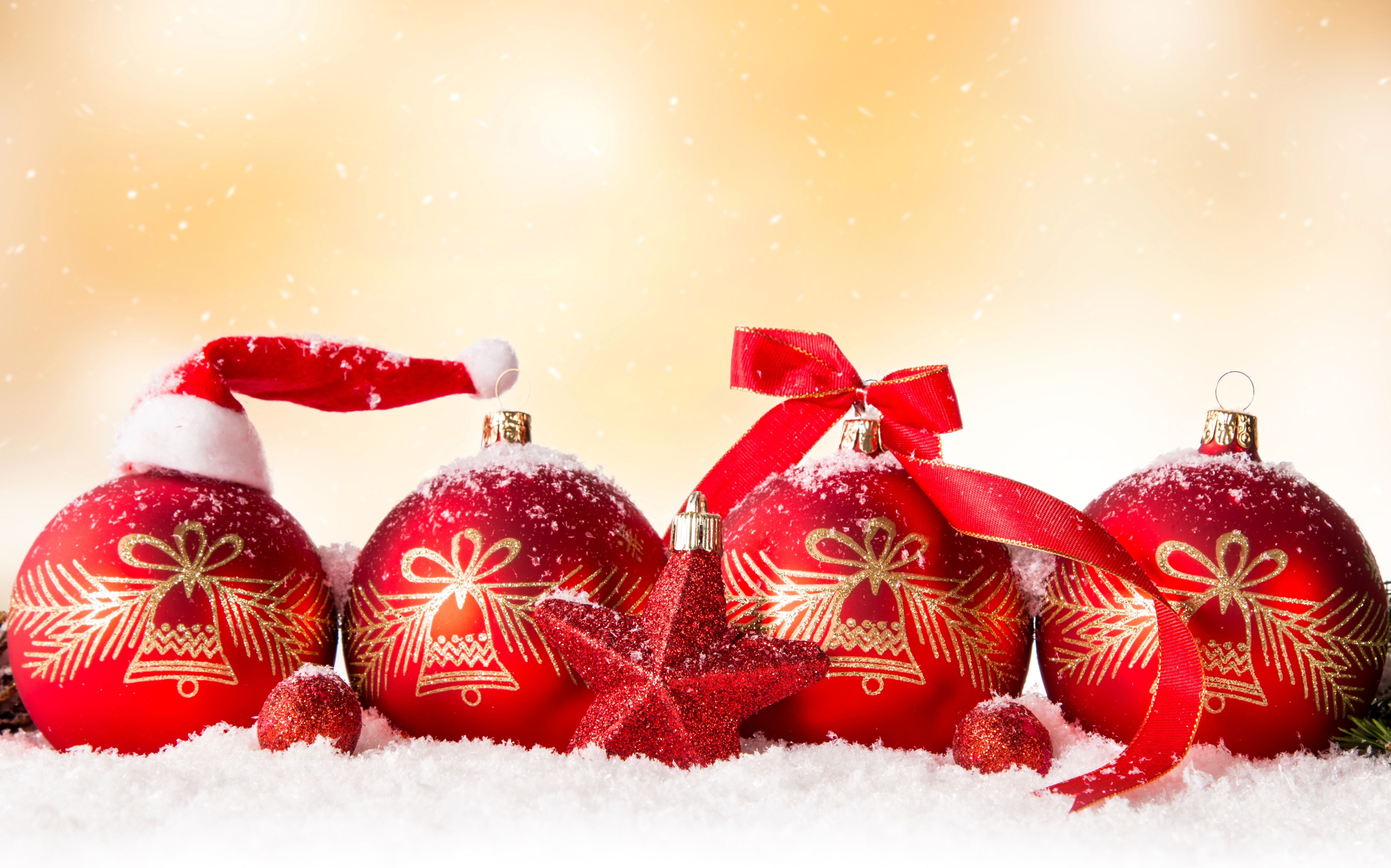 Red Christmas ornaments on snow with golden background