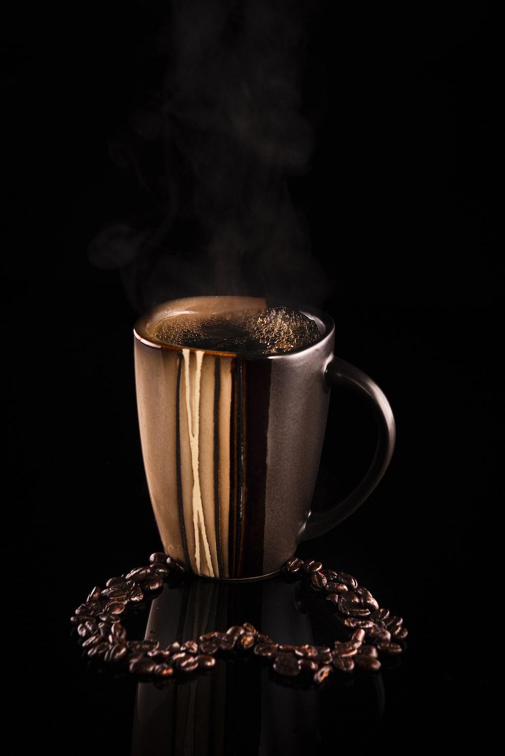 Brown And Black Ceramic Mug On White Table Cloth Photo