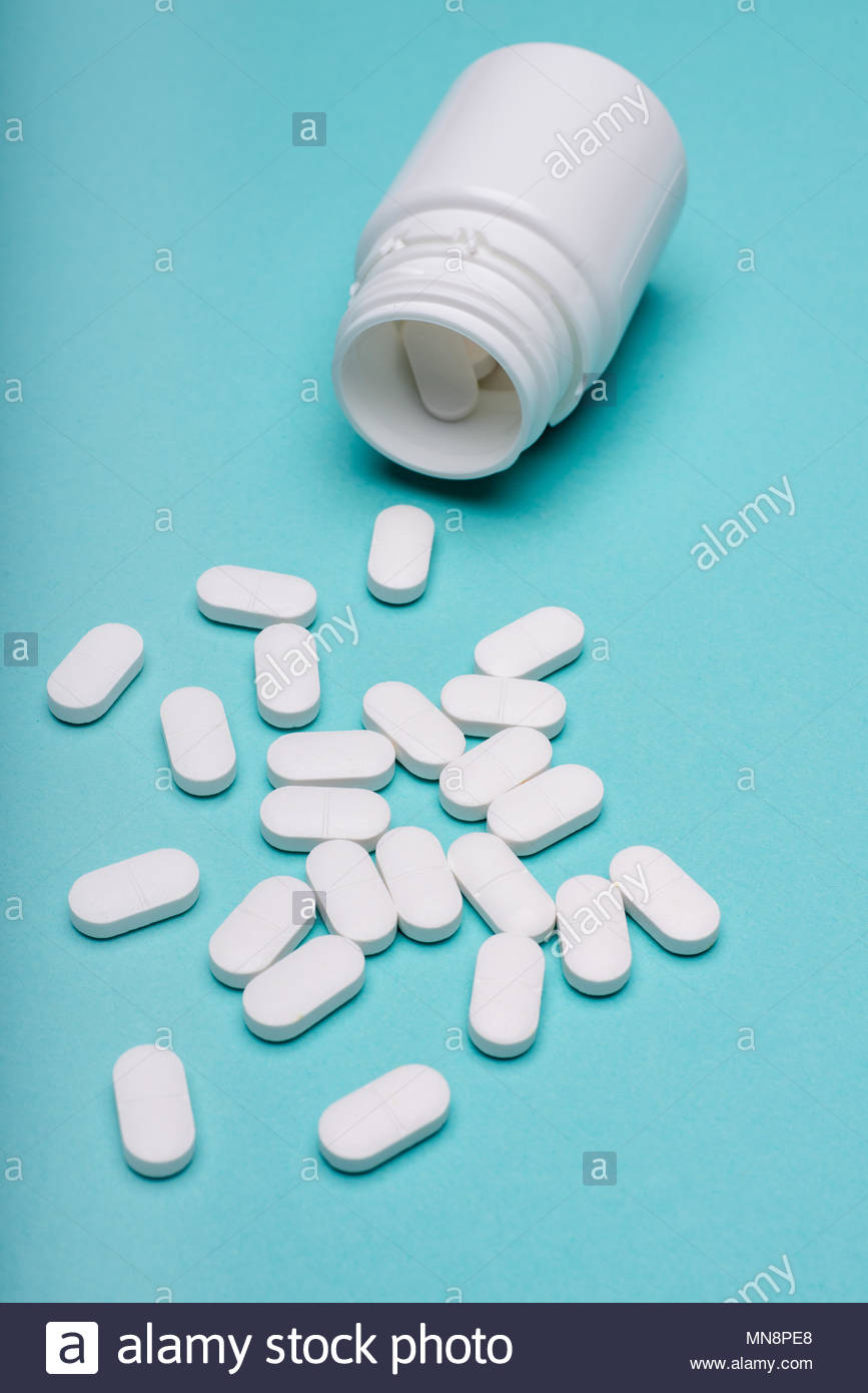 Medication Bottle And White Pills Spilled On Blue Pastel Coloured