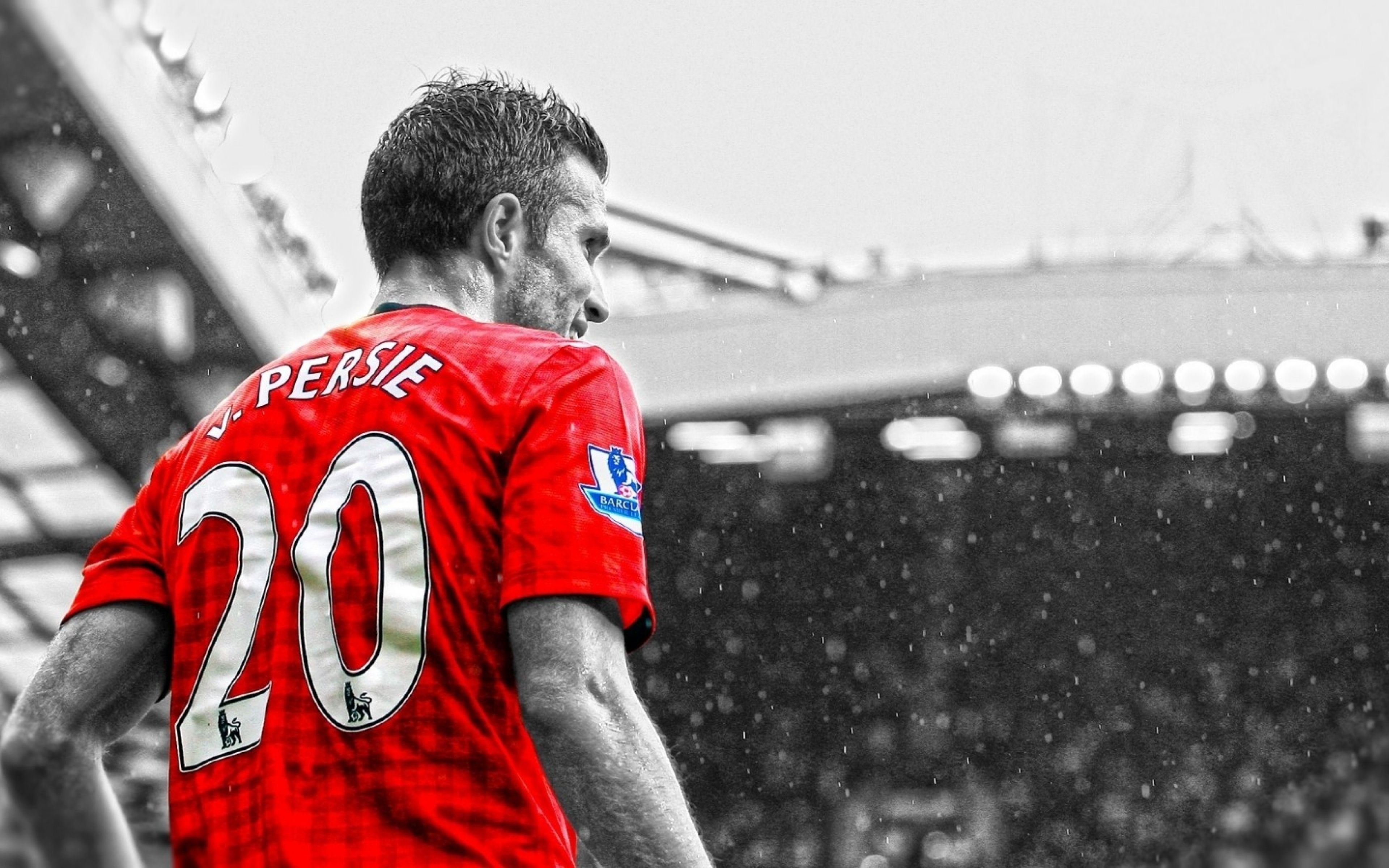 Robin van Persie in a Manchester United jersey, number 20, his back to the camera as he looks towards a rain-swept stadium