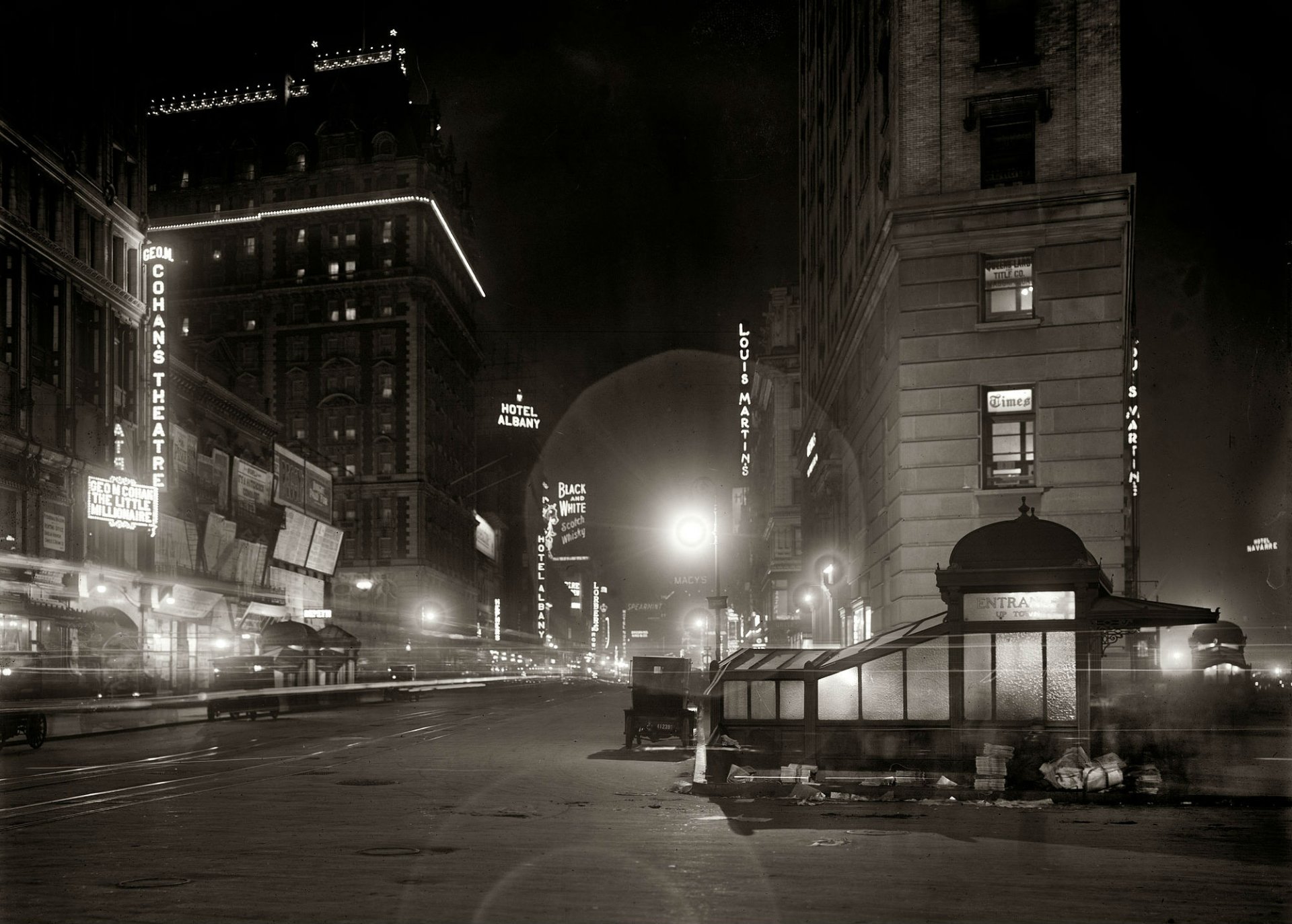 A vintage night scene of Broadway in New York City, illuminated by electric lights and signage, showcasing theaters, hotels, and bustling city life