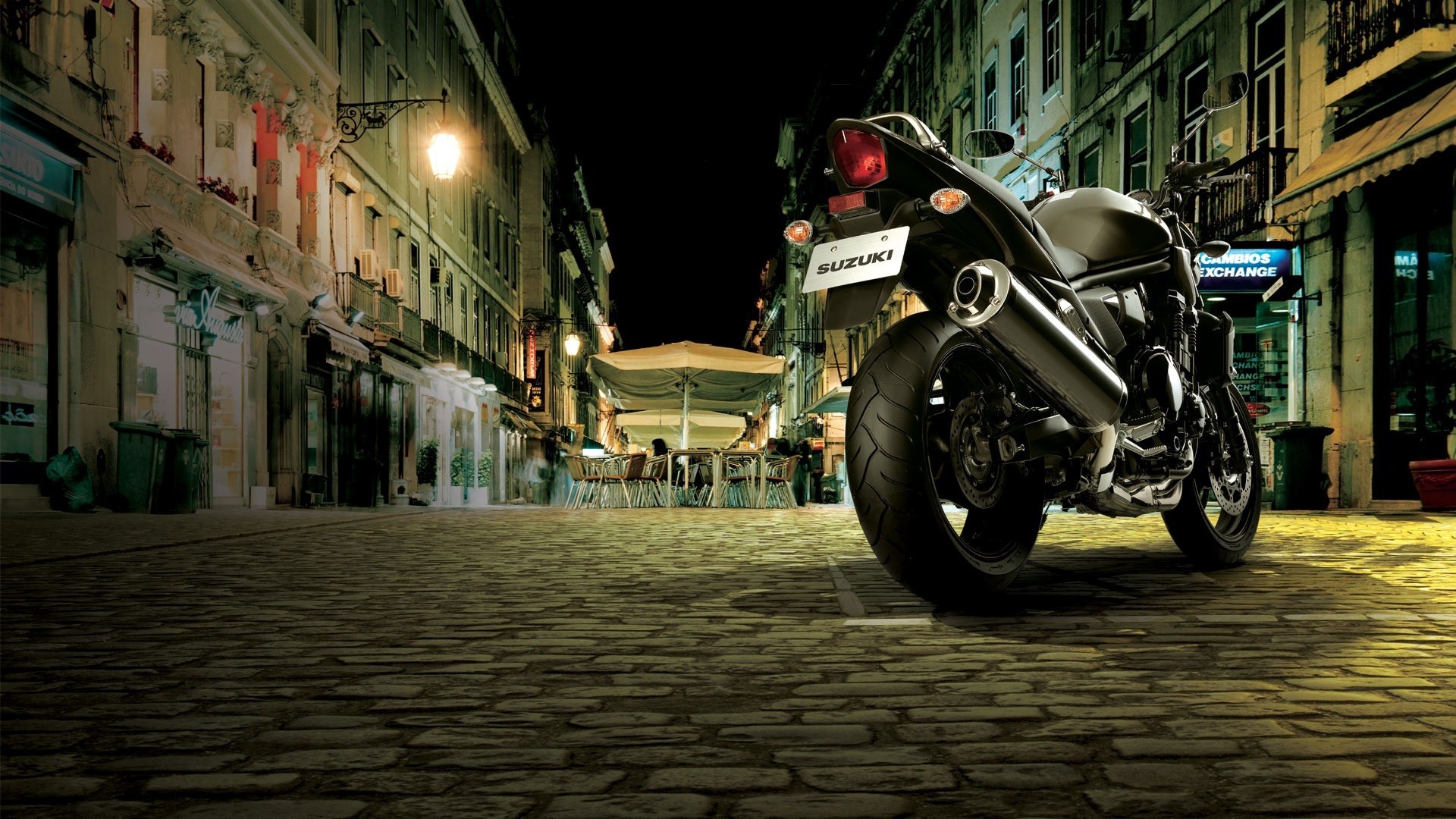 A black Suzuki motorcycle parked on a cobblestone street at night