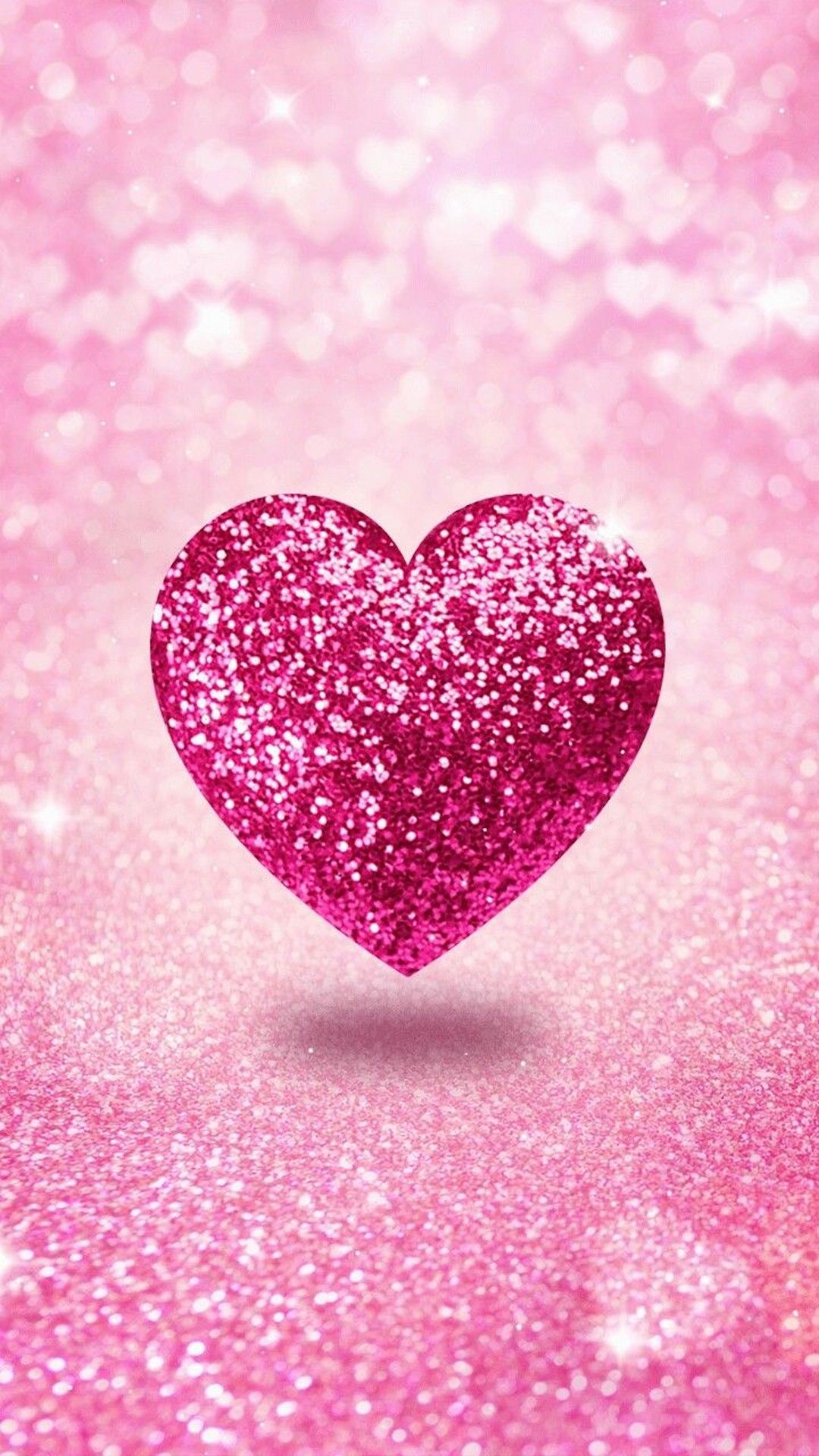 A sparkly pink glitter heart on a pink glitter background