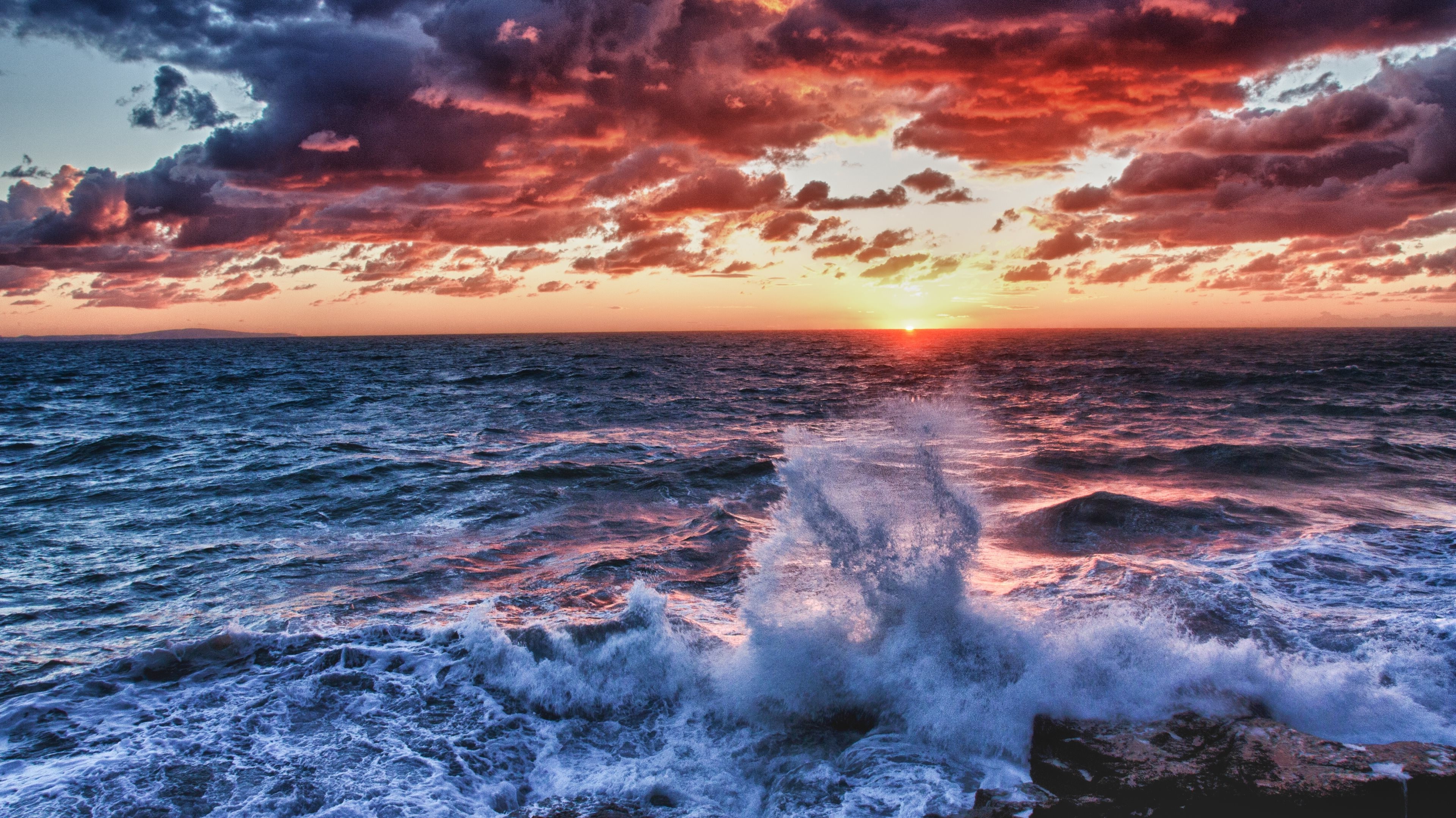Dramatic sunset over a stormy ocean with crashing waves