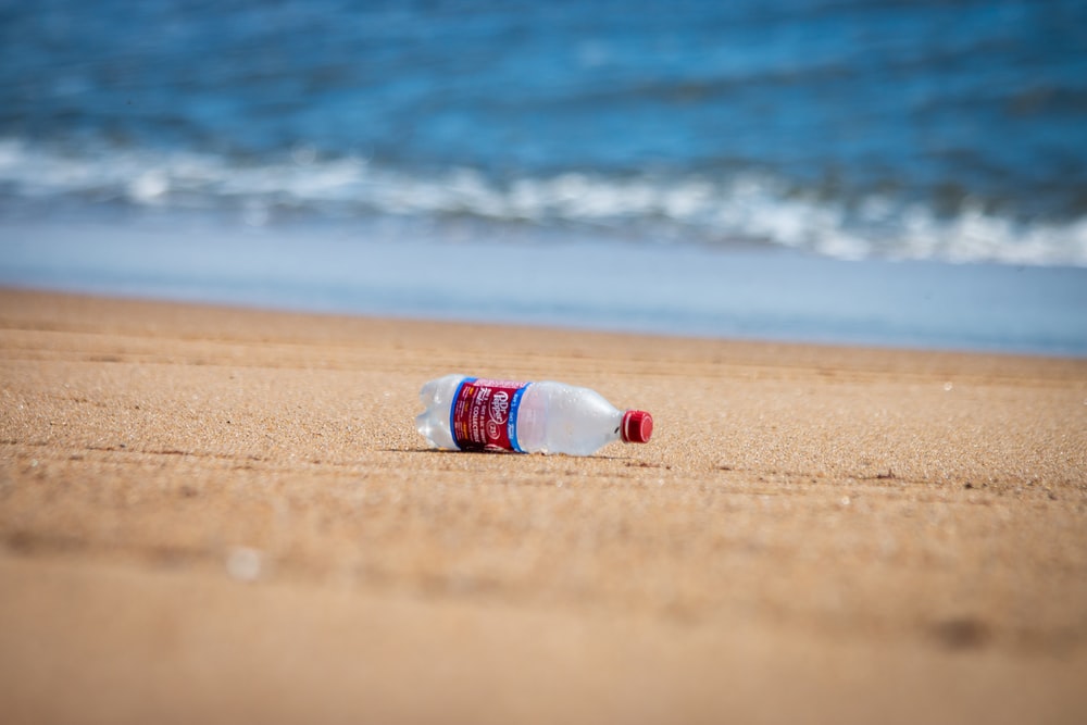 White And Blue Plastic Bottle On Beach Shore During Daytime Photo