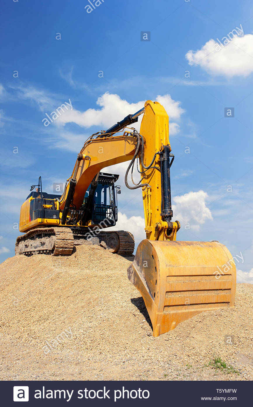 Yellow Excavator On A Pile Of Dirt With Blue Sky White Clouds
